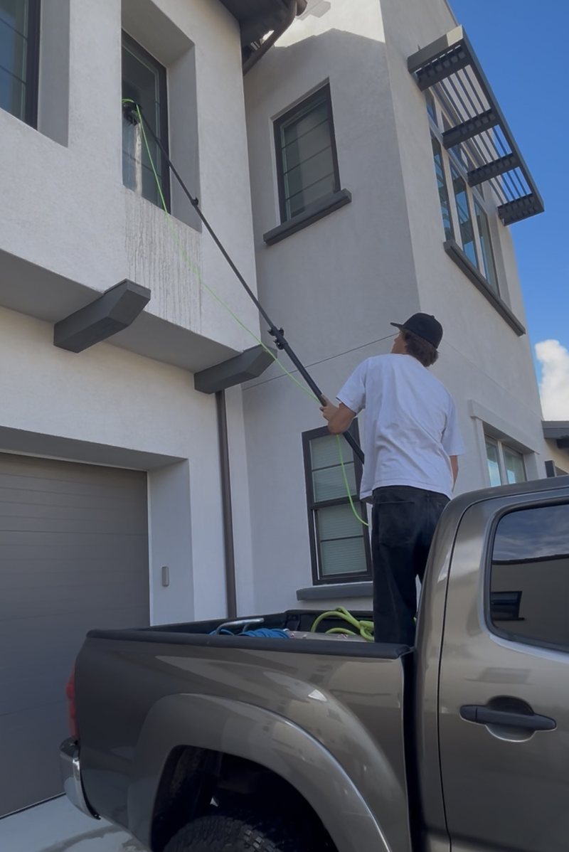 Pacific Pro owner working a second-storey window with a water-fed pole from the truck bed